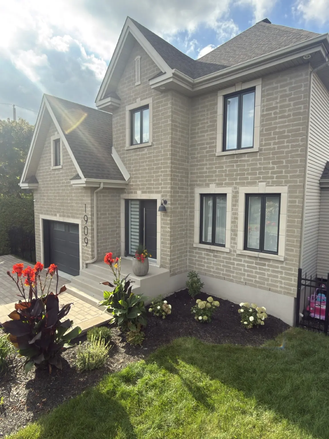 Maison en brique avec fleurs rouges et finition extérieure noire